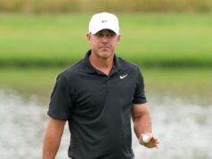 Koepka Drops Brutal Truth About LIV Golf’s Real Weakness Man in a black polo shirt and white Nike cap holding a golf ball on a golf course field.
