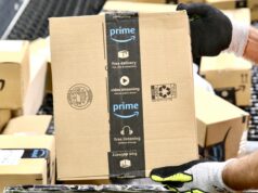 Golfer Battles Back Pain with Prime Day Recommendations Gloved hand gripping a cardboard Amazon Prime box in a warehouse setting.